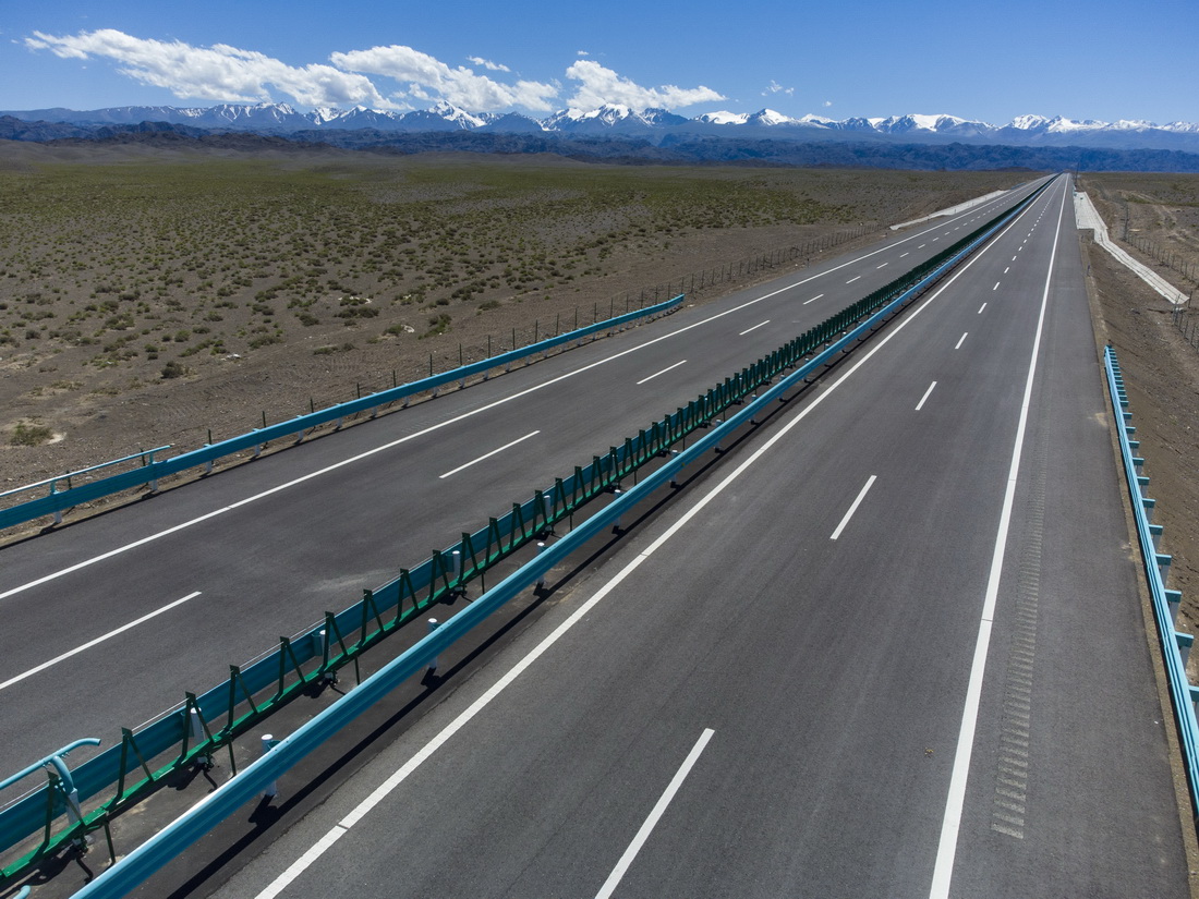 这是在新疆伊吾县拍摄的与雪山相伴的京新高速公路(6月29日摄,无人机